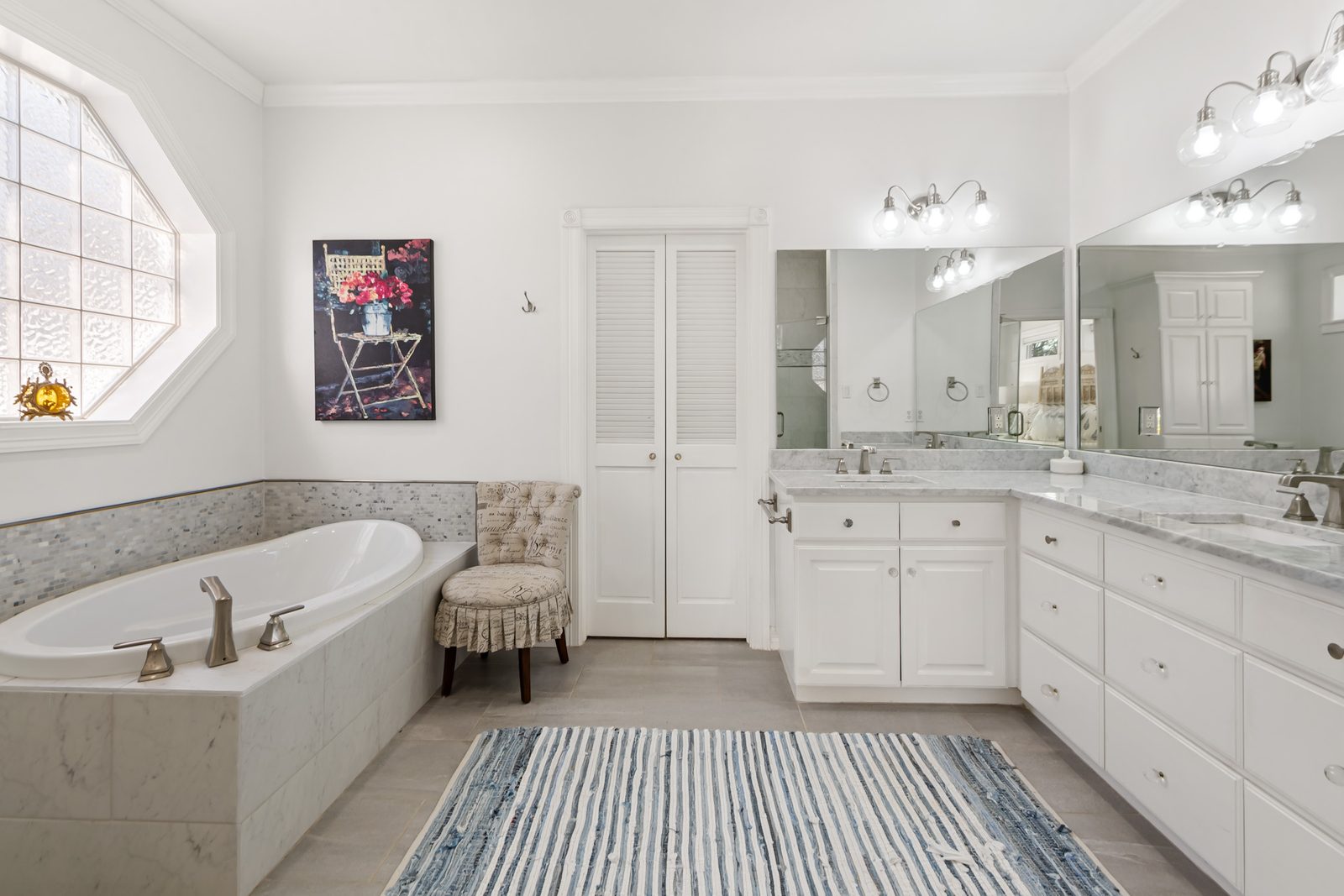 Primary bathroom with a soaking tub, double marble vanity, and glass shower
