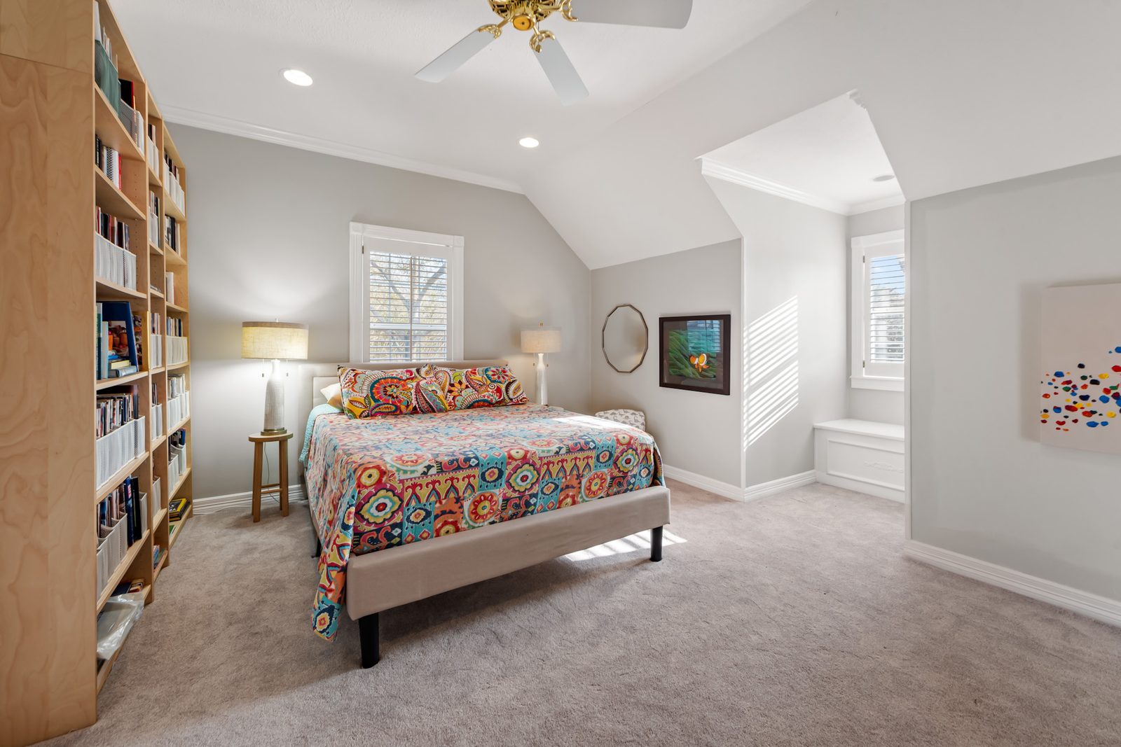 Upstairs bedroom with bookshelves, two windows, and an alcove