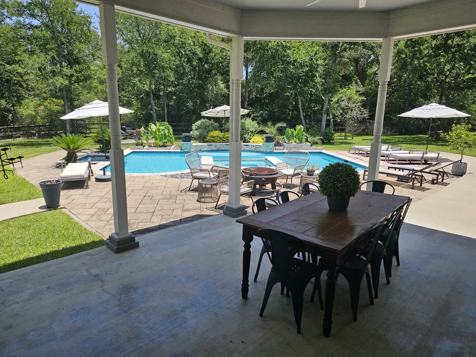 Covered outdoor dining overlooking the pool, spa, and wooded acreage