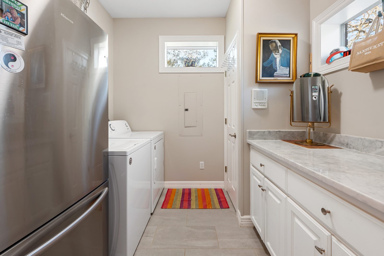 Downstairs laundry with washer, dryer, extra refrigerator, and a marble folding counter