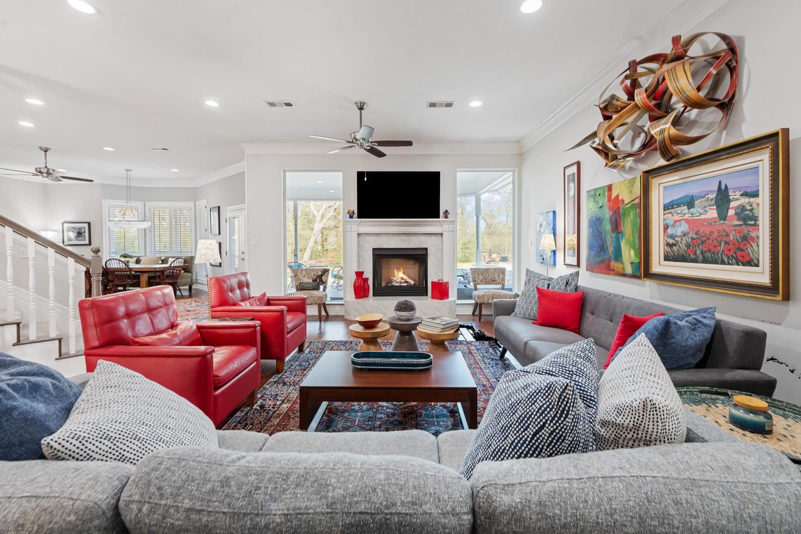 Open family room with fireplace, designer seating, and a wall of windows