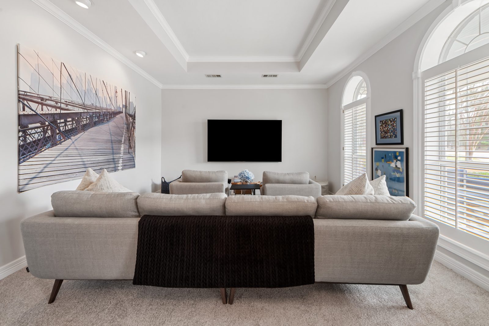 First-floor media room with a sectional sofa facing a wall-mounted television