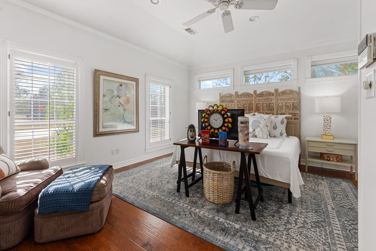 Primary bedroom with sitting area, clerestory windows, and a carved wood headboard